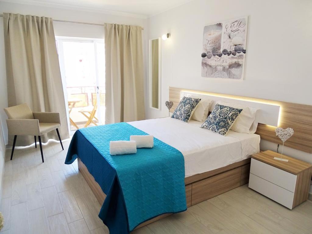 una camera da letto con un grande letto con una coperta blu di Luz Apartments a Portimão