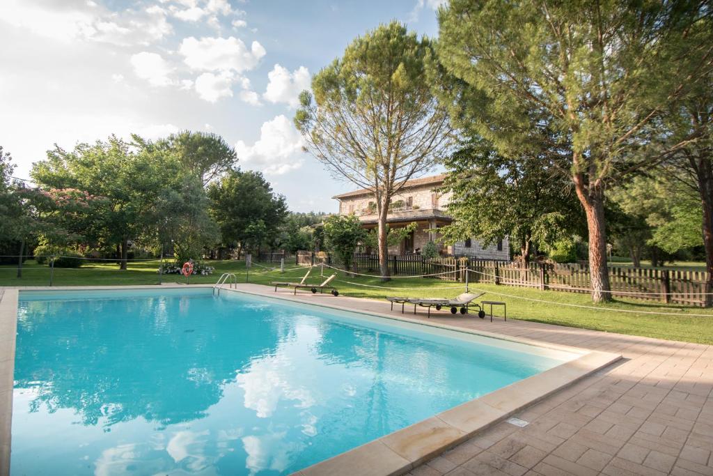 a swimming pool with a bench and a house at Agriturismo Il Giardino Dei Ciliegi in Passaggio Di Assisi