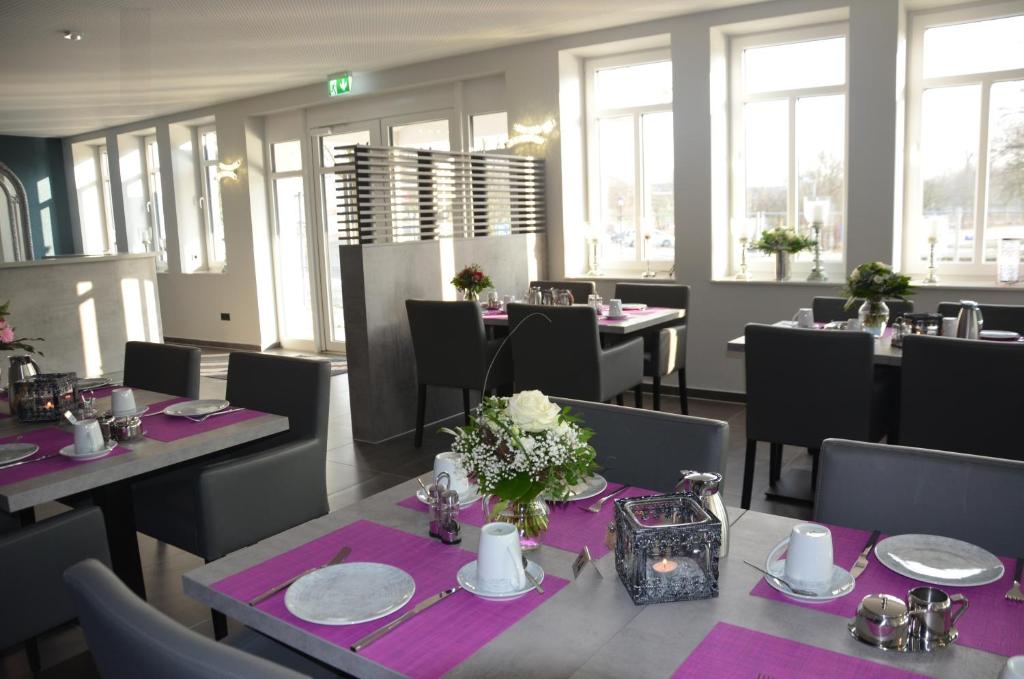 uma sala de jantar com mesas e cadeiras com mesa roxa em Hotel Garni Nordseejuwel em Horumersiel