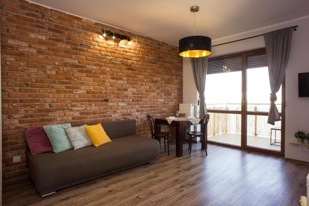 Atrium Apartment z garażem في تورون: غرفة معيشة مع أريكة وجدار من الطوب