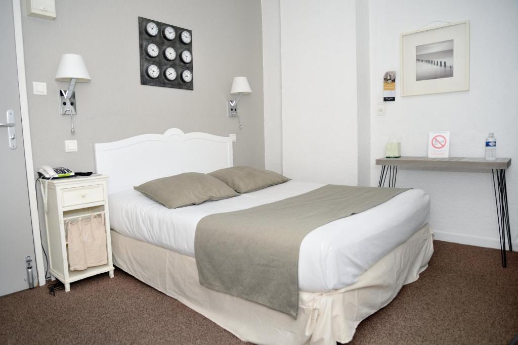 una camera da letto con un grande letto bianco e un tavolo di EtC...Hôtel - Strasbourg Hyper Centre a Strasburgo
