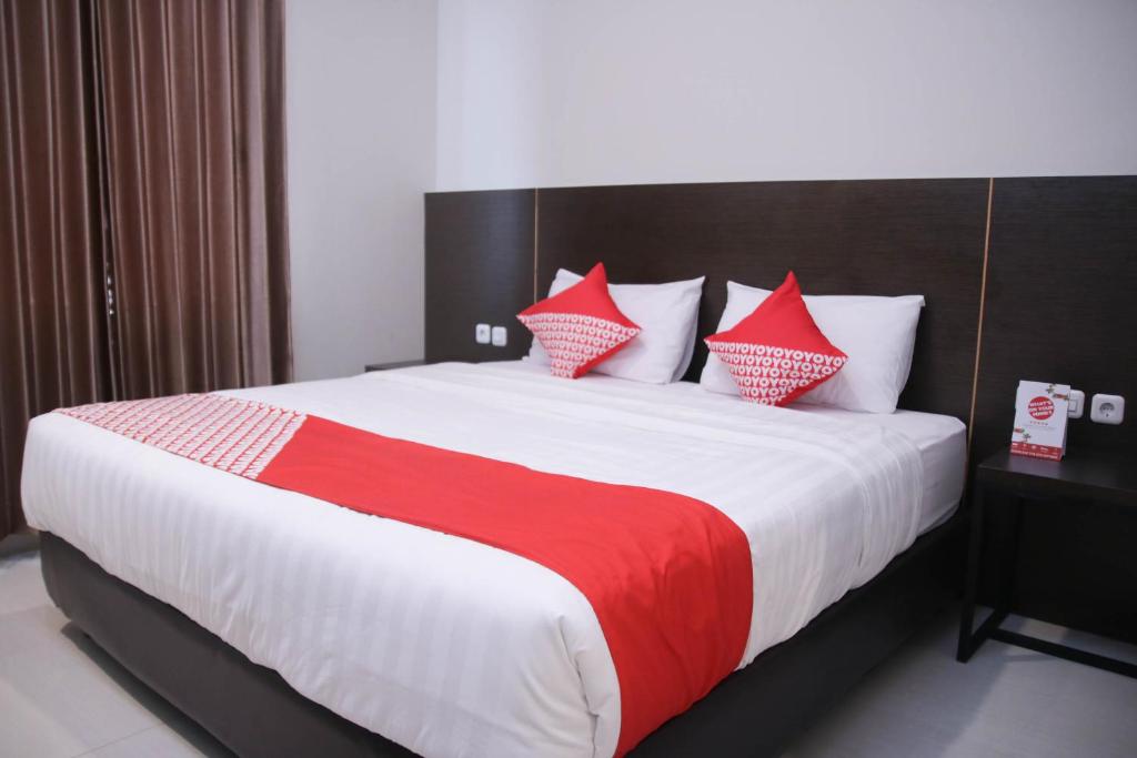 a bedroom with a large bed with red and white pillows at Super OYO 1006 Azzahra Guest House Syariah in Ambon