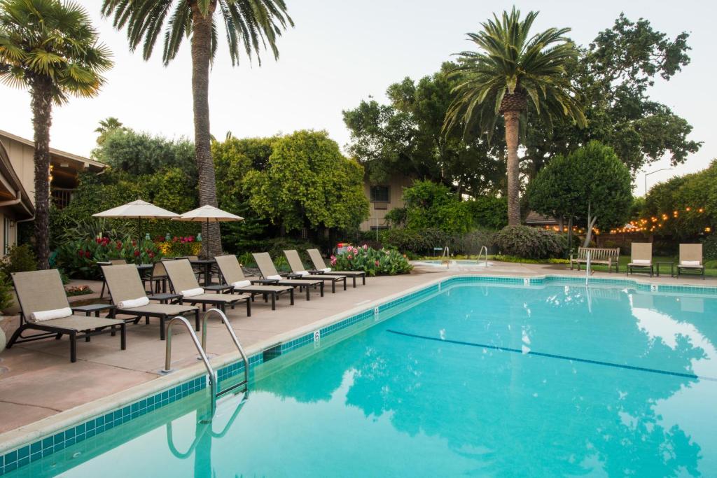 uma piscina com cadeiras e palmeiras em El Pueblo Inn em Sonoma