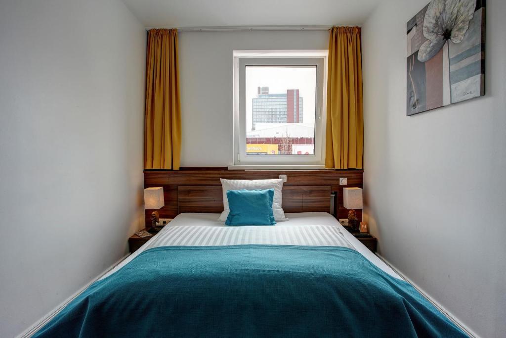 a small bedroom with a bed with a window at North-Hotel in Hamburg