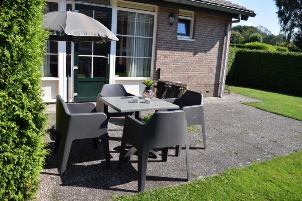 a table and chairs and an umbrella in front of a house at Bunckman 10 pers. bungalow in Voorthuizen