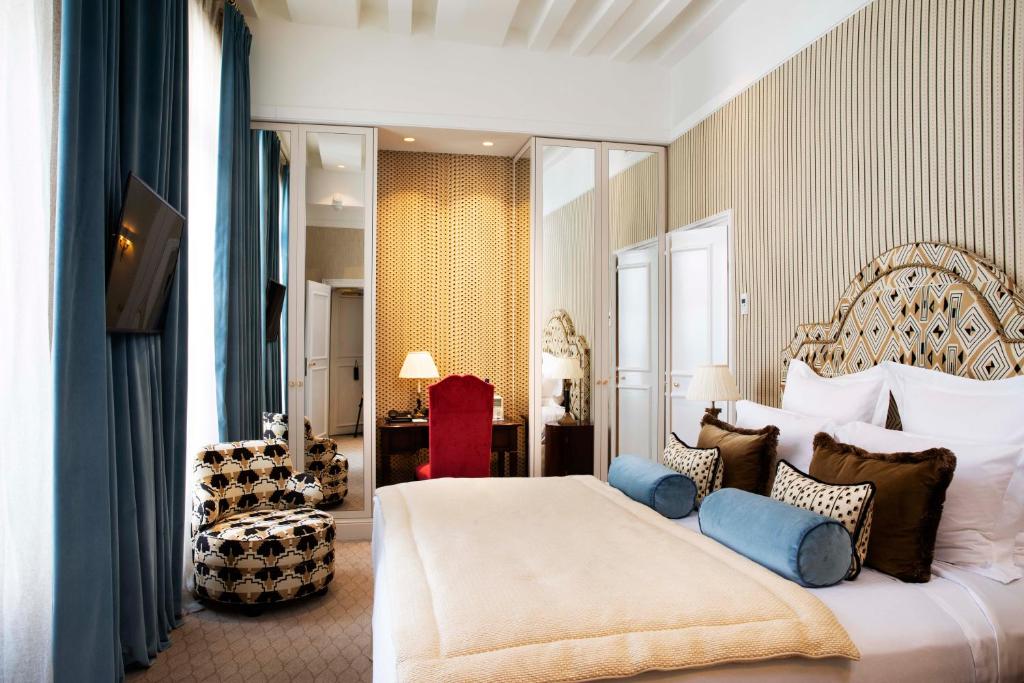 a bedroom with a large bed with blue pillows at Relais Christine in Paris