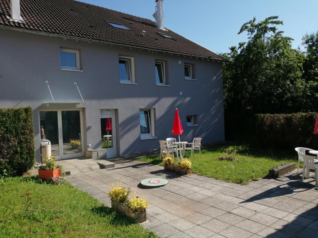 a house with a patio with a table and a red umbrella at Mamyvonne Vacances in Tendon