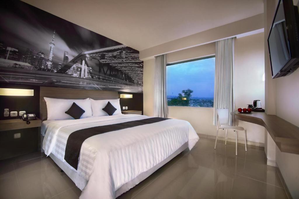 a bedroom with a large bed and a large window at Hotel Neo Candi Simpang Lima - Semarang by ASTON in Semarang