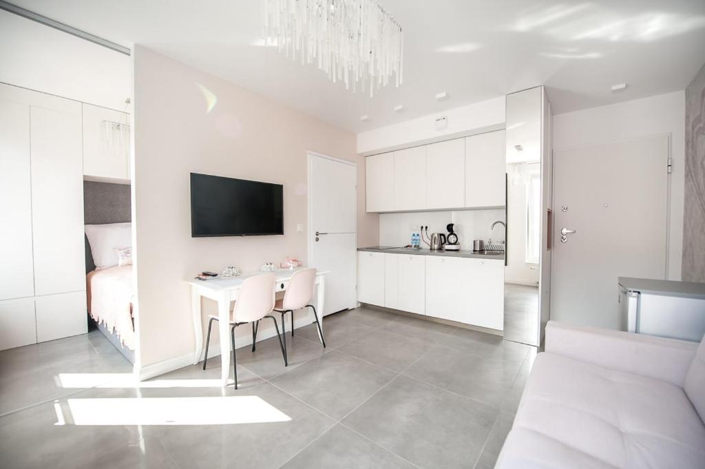 uma cozinha branca com uma mesa e cadeiras num quarto em Amelia Suite em Gdansk