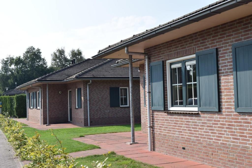 a red brick house with windows on the side of it at Ganzebeek 14 pers. bungalow in Voorthuizen