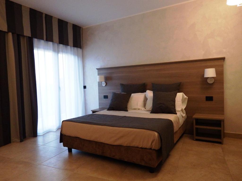 a bedroom with a large bed and a large window at La Giummara Rooms in Salemi