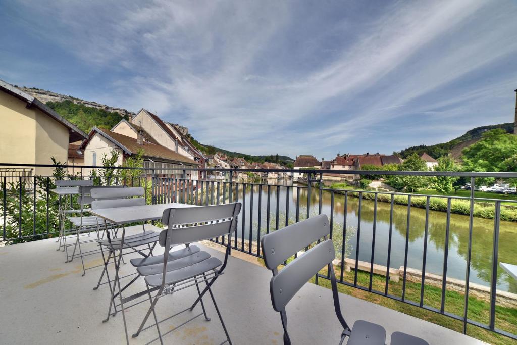 a balcony with chairs and tables and a view of a river at LES TANNERIES in Ornans