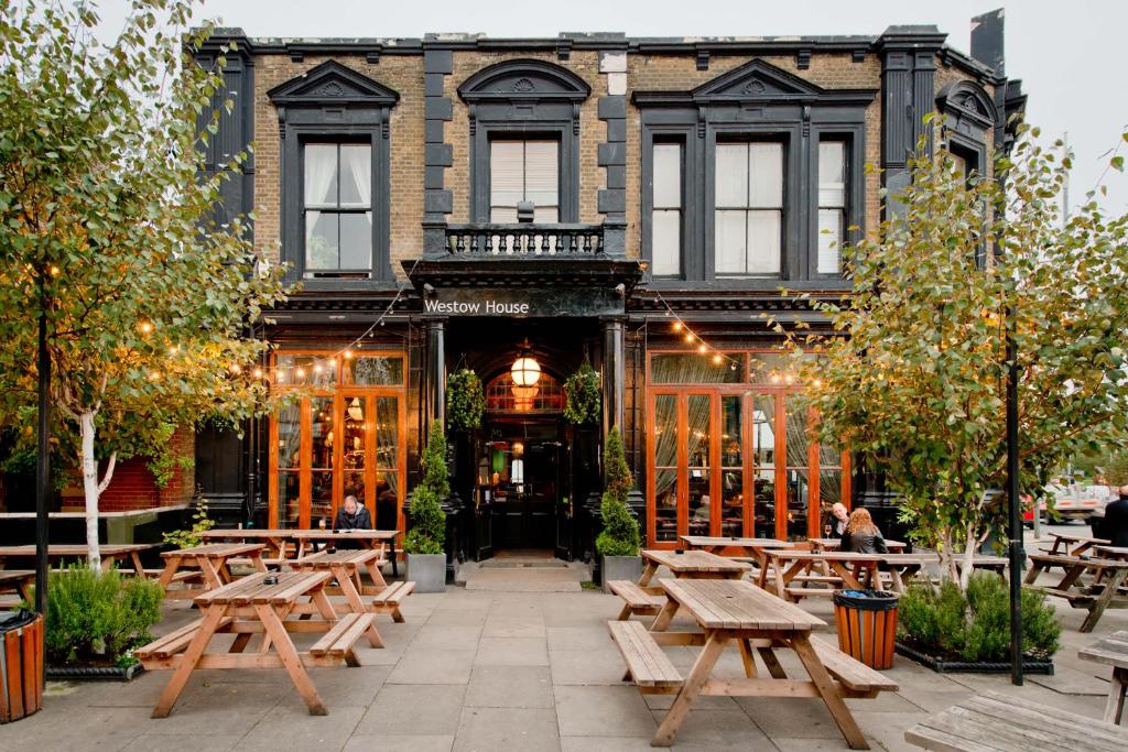 een restaurant met houten tafels voor een gebouw bij Westow House in Crystal Palace