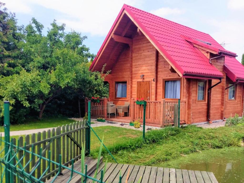 Casa de madera con techo rojo y valla en Domki Żabi Staw, en Mikołajki