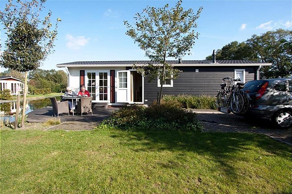 a woman sitting at a table in front of a house at Korhoen 4 persons in Rijssen