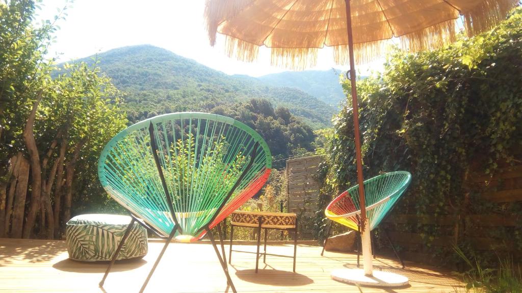 zwei Stühle unter einem Schirm auf einer Terrasse in der Unterkunft A Casa Catalina B&B in Ucciani