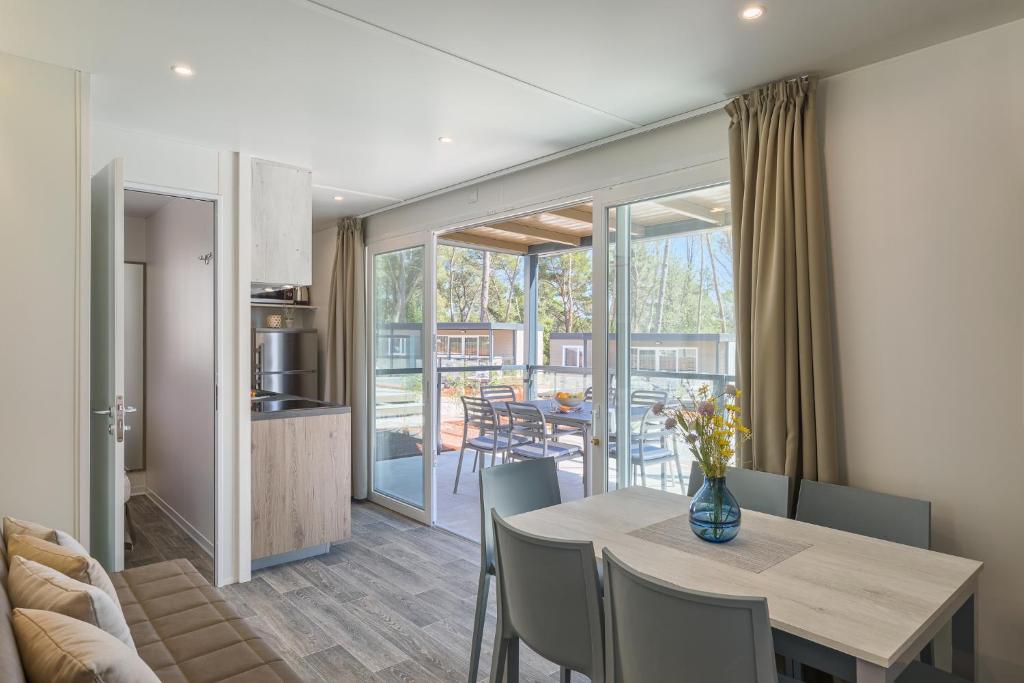 a dining room and kitchen with a table and chairs at Mobile Homes Camping Santa Marina, Lanterna in Poreč