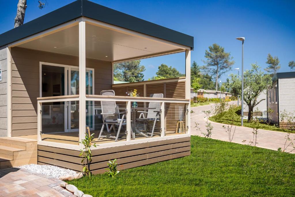 a house with a wrap around deck with chairs on it at Mobile Homes Camping Santa Marina, Lanterna in Poreč