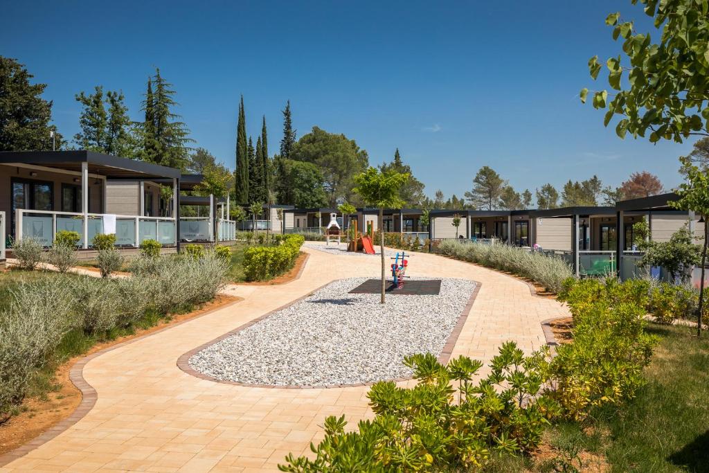 a garden with a building and a pathway at Mobile Homes Camping Santa Marina, Lanterna in Poreč