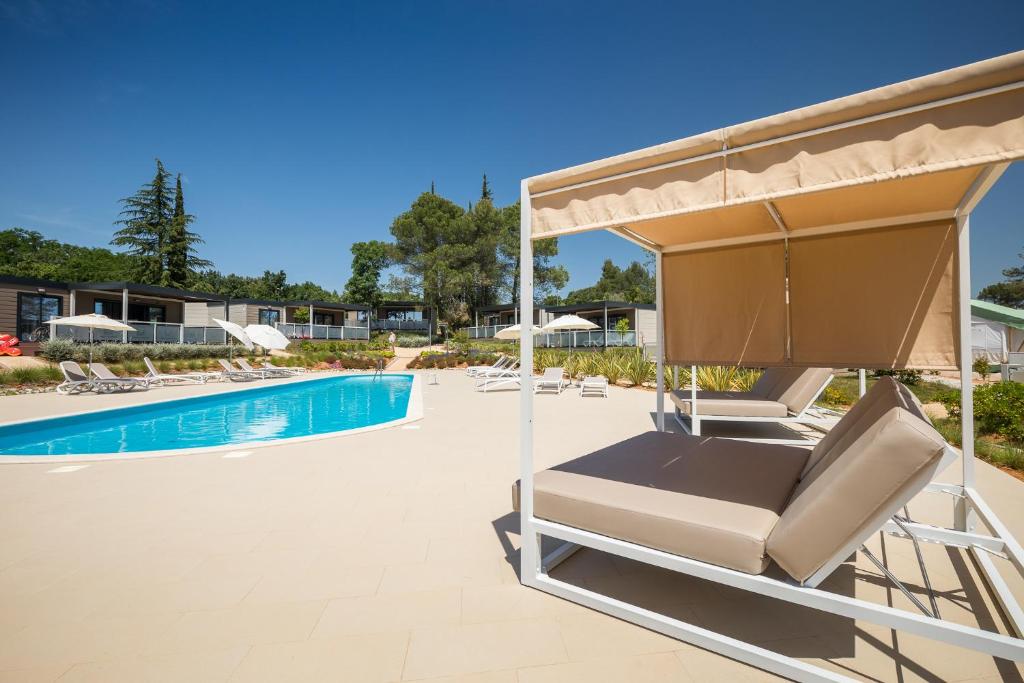 a swimming pool with chairs and a swimming poolvisorvisor at Mobile Homes Camping Santa Marina, Lanterna in Poreč