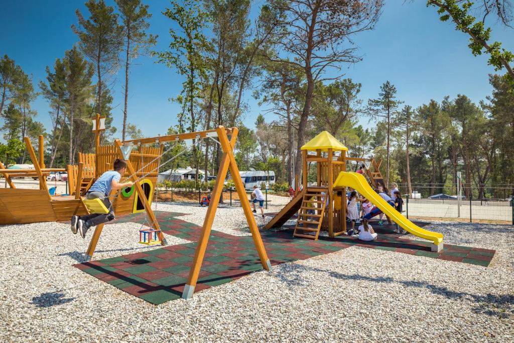 a boy playing on a swing set at a playground at Mobile Homes Camping Santa Marina, Lanterna in Poreč