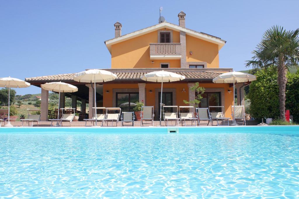 a villa with a swimming pool in front of a house at Country House La Foggetta in Pineto