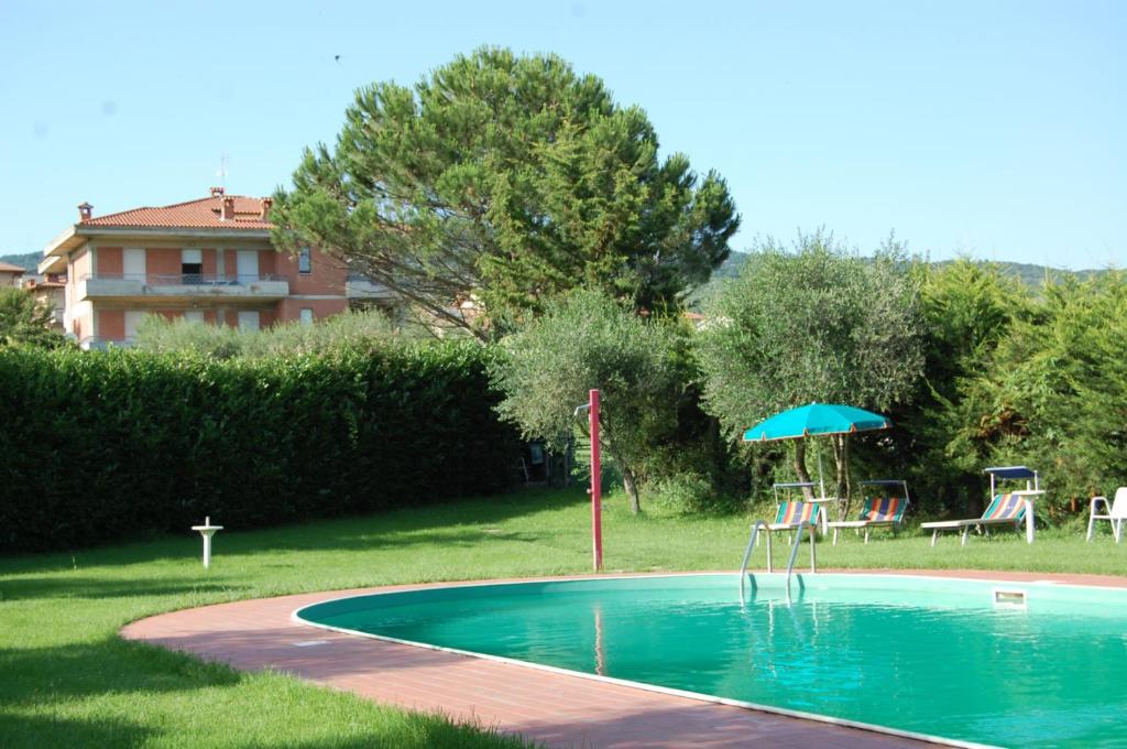 a swimming pool with an umbrella and a table and chairs at Tommaso 2 Sopra in Tuoro sul Trasimeno