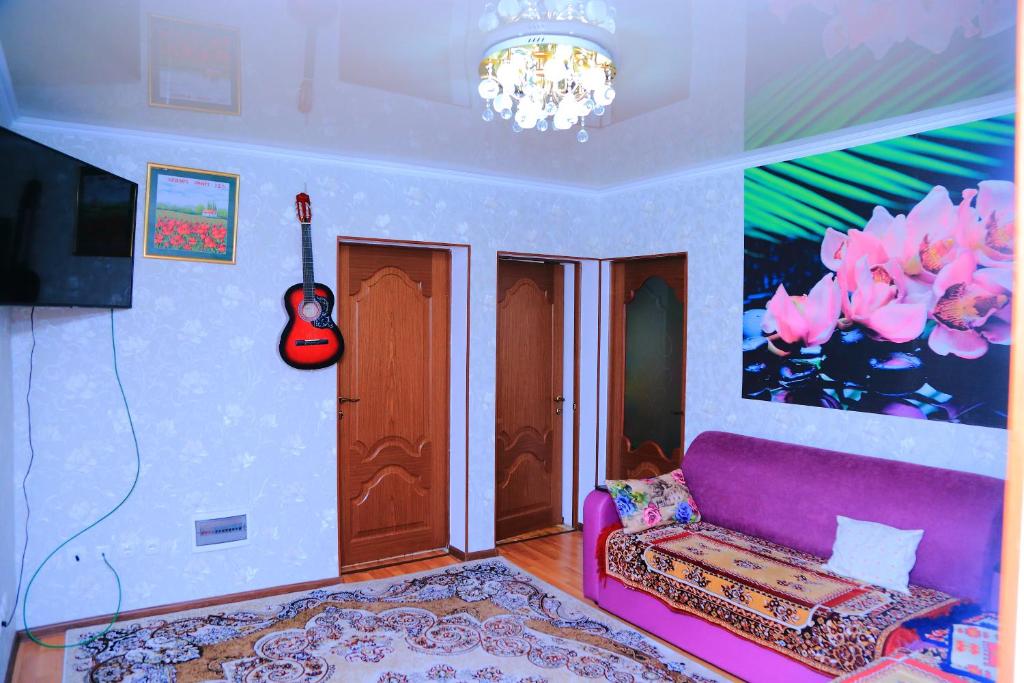 a living room with a purple couch and a guitar at Guest House Jamal in Naryn