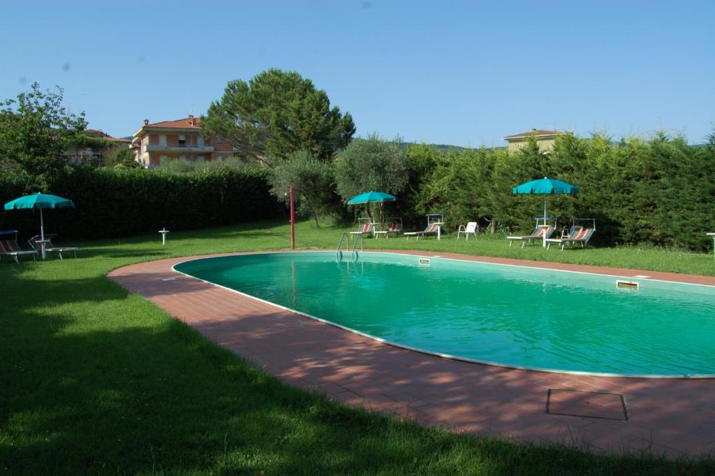 una piscina con sillas y sombrillas en un patio en Tommaso 5, en Tuoro sul Trasimeno