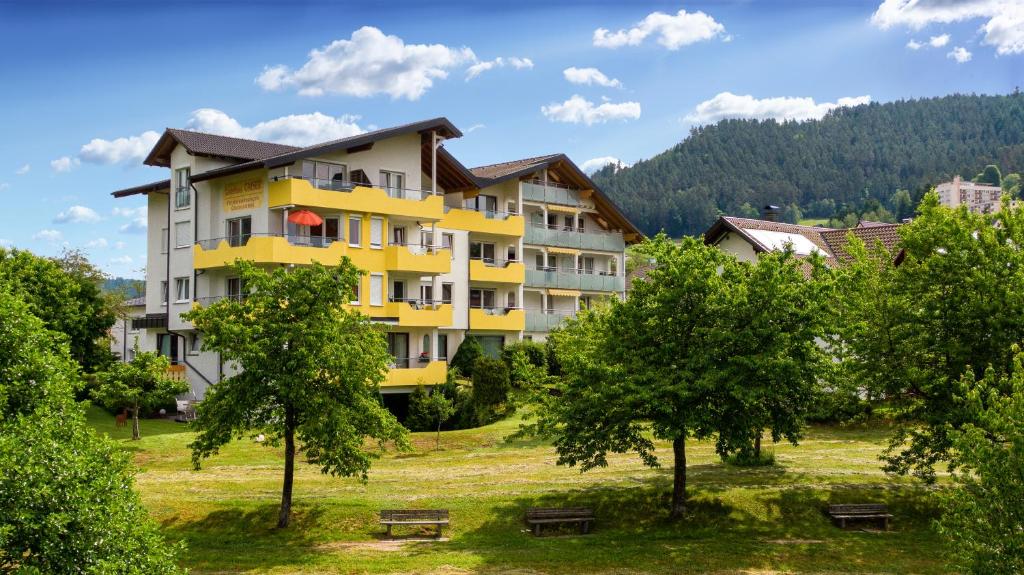 żółty budynek apartamentowy w parku z drzewami w obiekcie Gästehaus Gaiser w mieście Baiersbronn