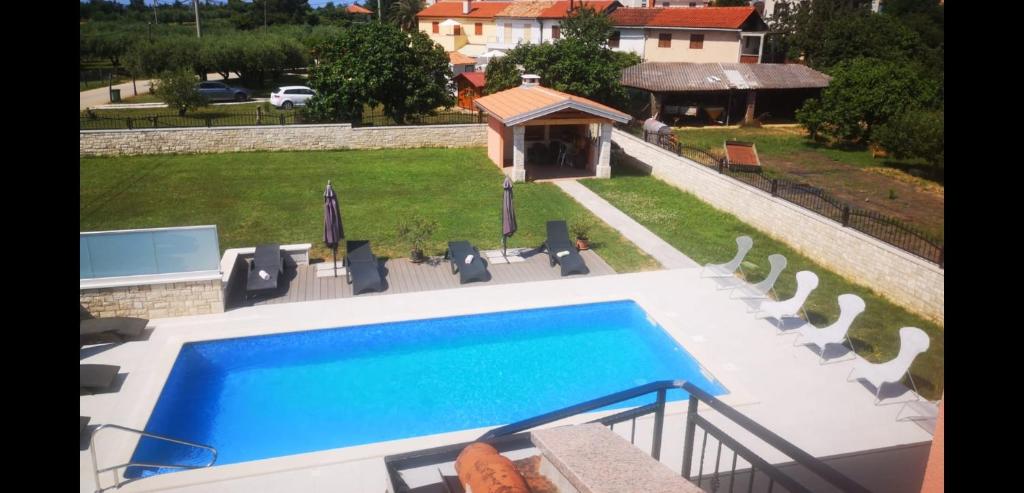 a view of a swimming pool with chairs and a house at Apartments Alma in Crveni Vrh