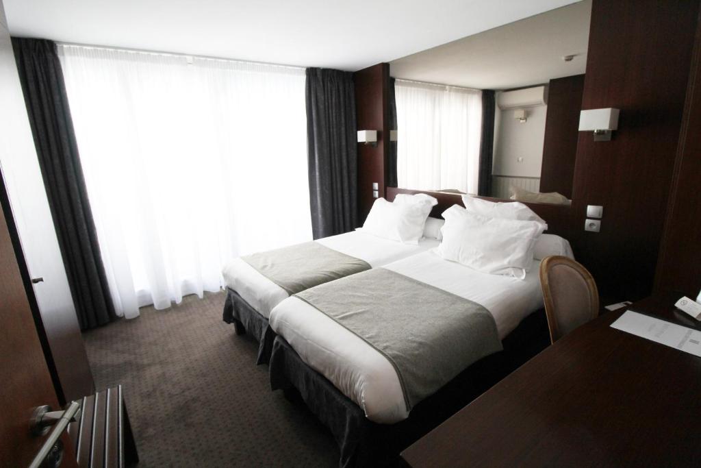 ストラスブールにあるHotel des Tonneliersの大きなベッドと窓が備わるホテルルームです。