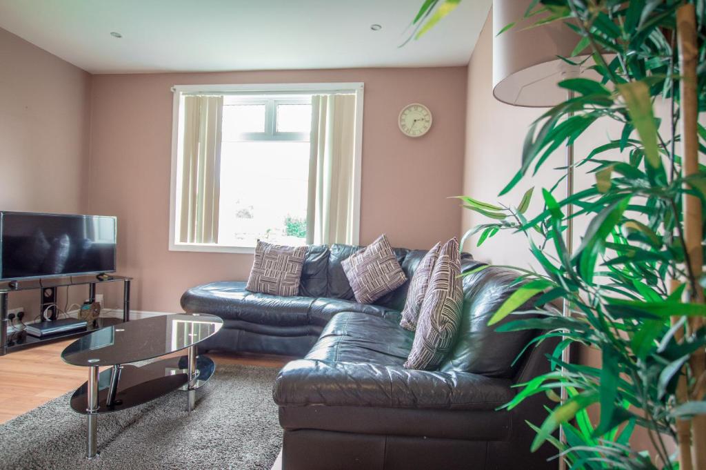 uma sala de estar com um sofá de couro e uma mesa em Montgomery Apartments - Stevensons em Edimburgo