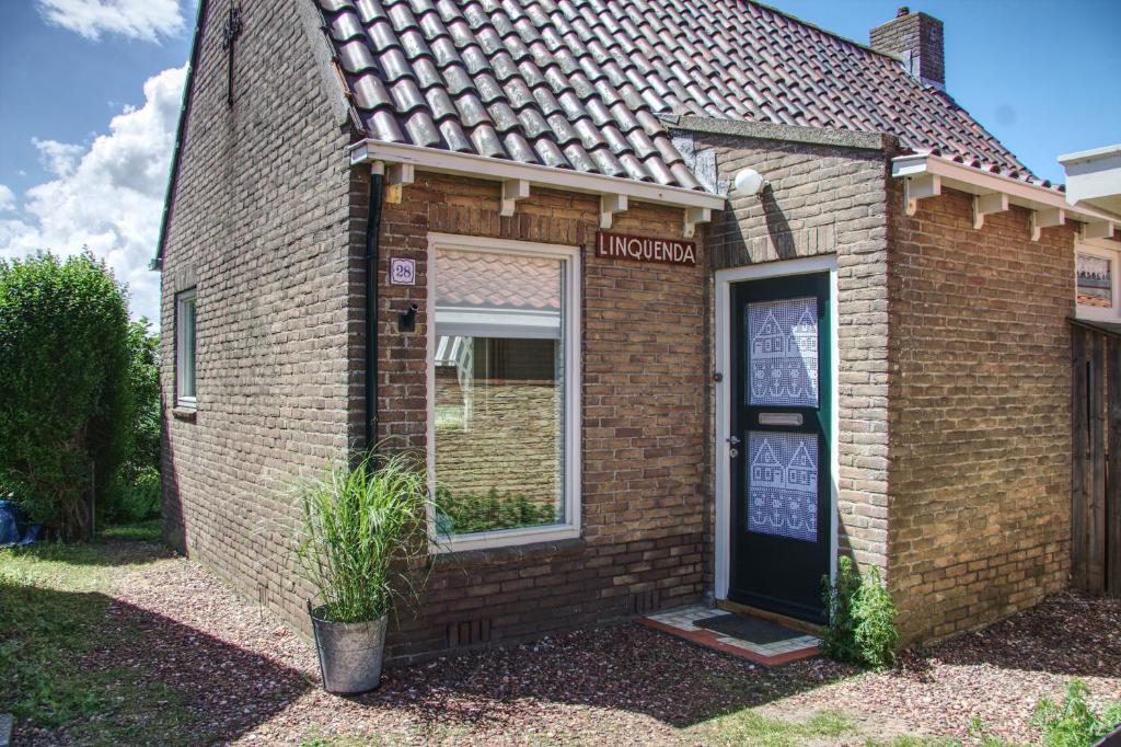 a brick building with a window and a door at Huisje Linquenda in Moddergat