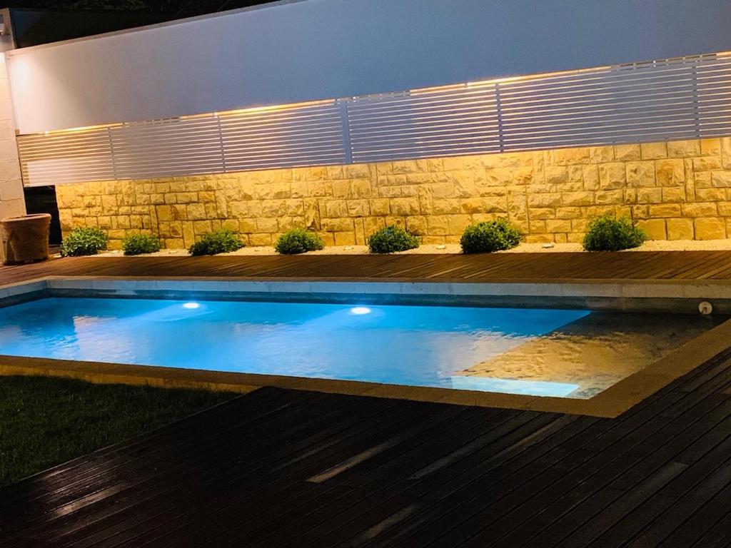a swimming pool with lights in a backyard at night at White Villa in Selva di Fasano