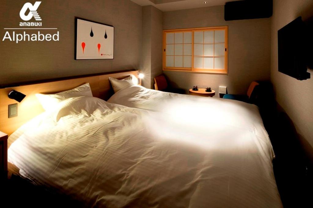 a bedroom with a bed with white sheets and a sign at ALPHABED INN Takamatsuekimae 305 / Vacation STAY 36566 in Takamatsu