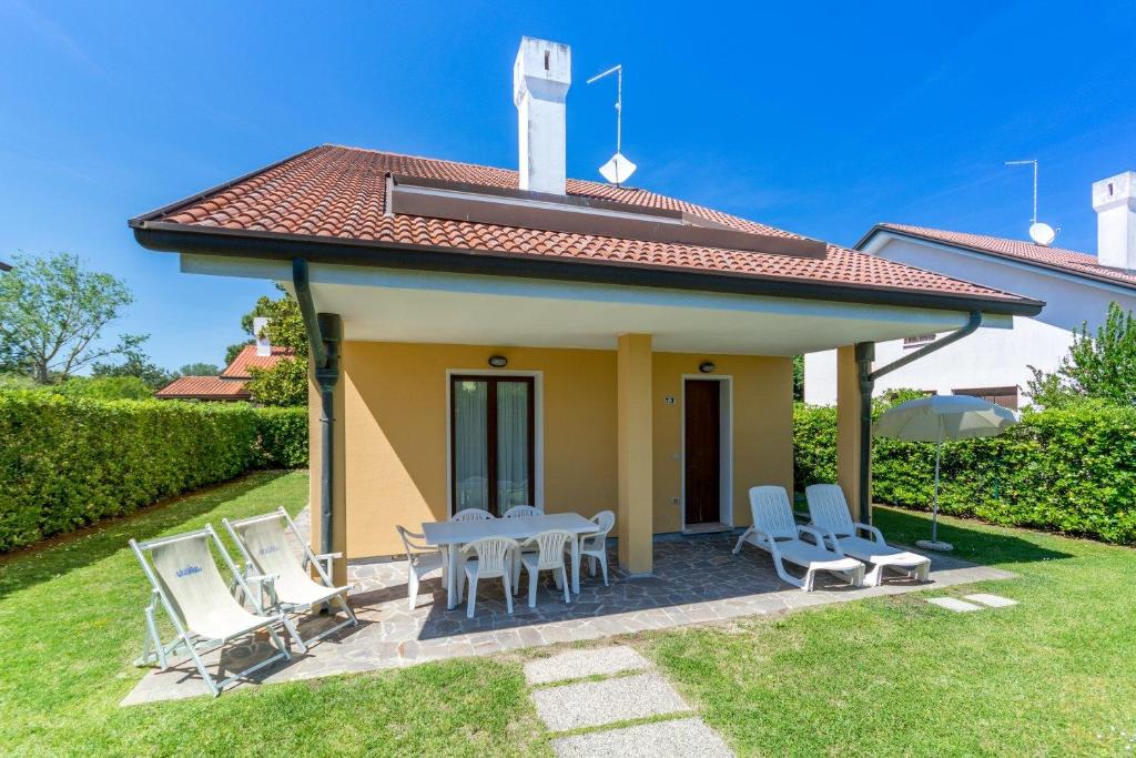 una pequeña casa amarilla con mesa y sillas en Villa V4 bi-trifamiliare, en Isola Albarella