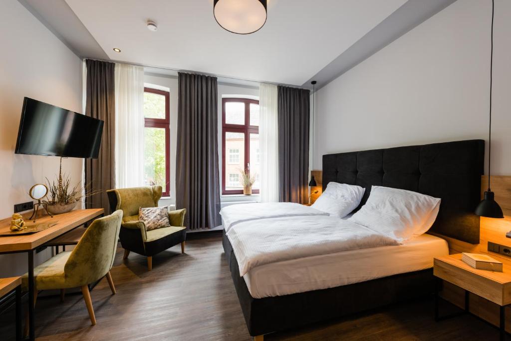 a bedroom with a large bed and a desk and a chair at 360 Grad Hotel & Bar in Leer