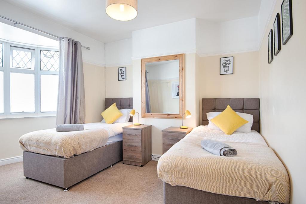 a bedroom with two beds and a mirror at The Location - TV in Every Bedroom! in Swansea