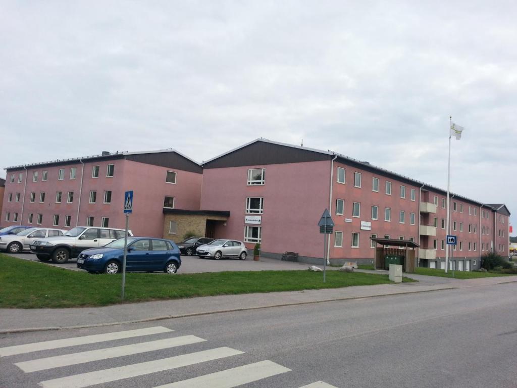 ein großes rosafarbenes Gebäude mit Autos auf einem Parkplatz in der Unterkunft Vandrarhem Köping in Köping