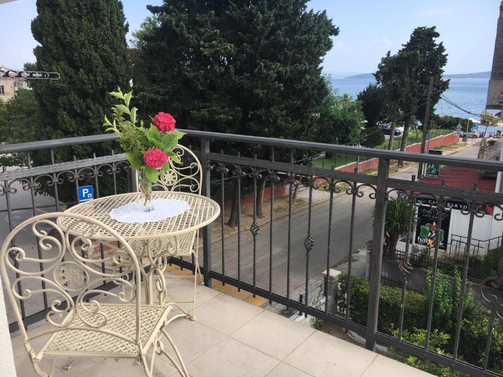 una mesa con un jarrón de flores en el balcón en Courtyard seafront house, en Kaštela