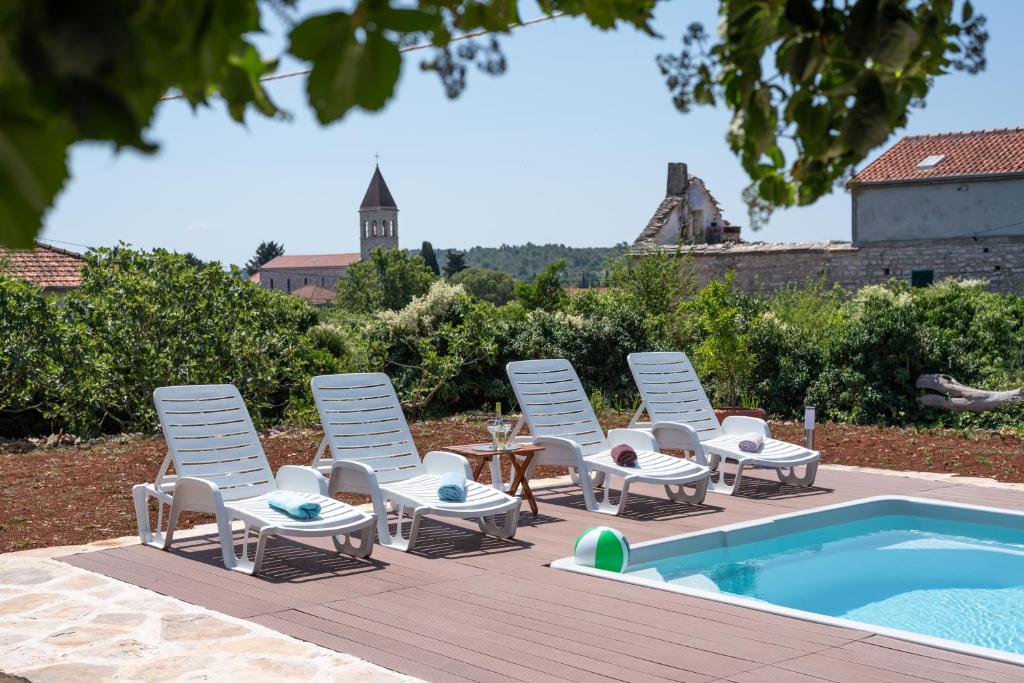 eine Gruppe Stühle und ein Tisch neben einem Pool in der Unterkunft Holiday House Markoč in Grohote