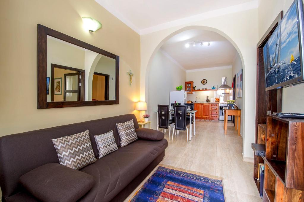 a living room with a brown couch and a kitchen at aloha apartments in Marsalforn