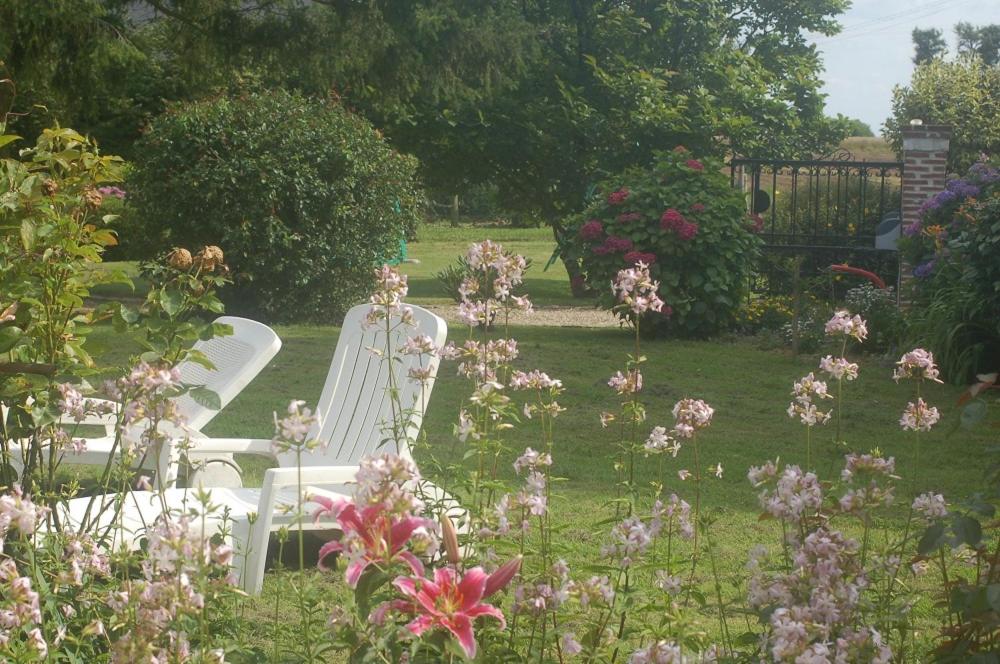 zwei weiße Stühle in einem Garten mit Blumen in der Unterkunft La Polaris in Angerville-lʼOrcher