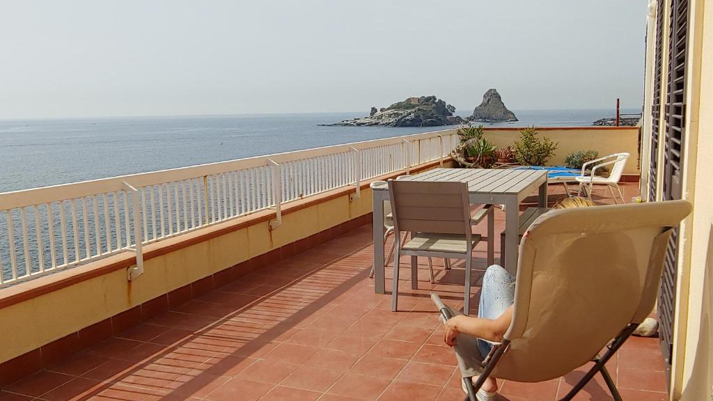 Una donna seduta su un balcone che guarda l'oceano di casa Ciclopi ad Acitrezza