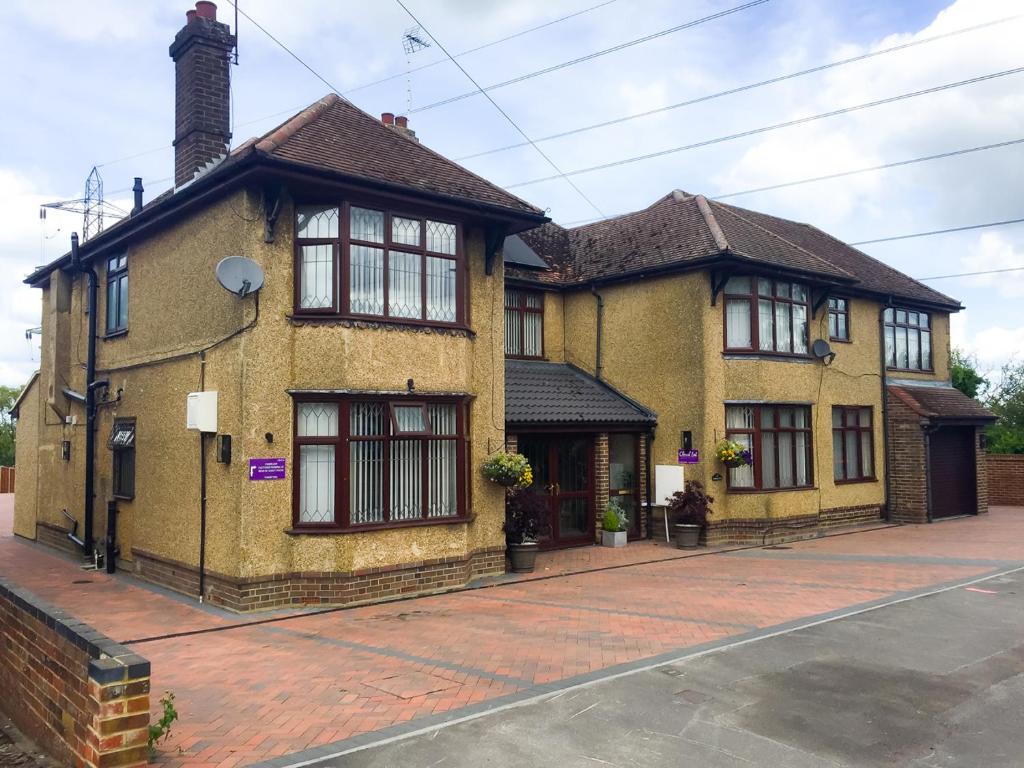 a yellow brick house with windows on a street at Cherish End Guest House in Dunstable