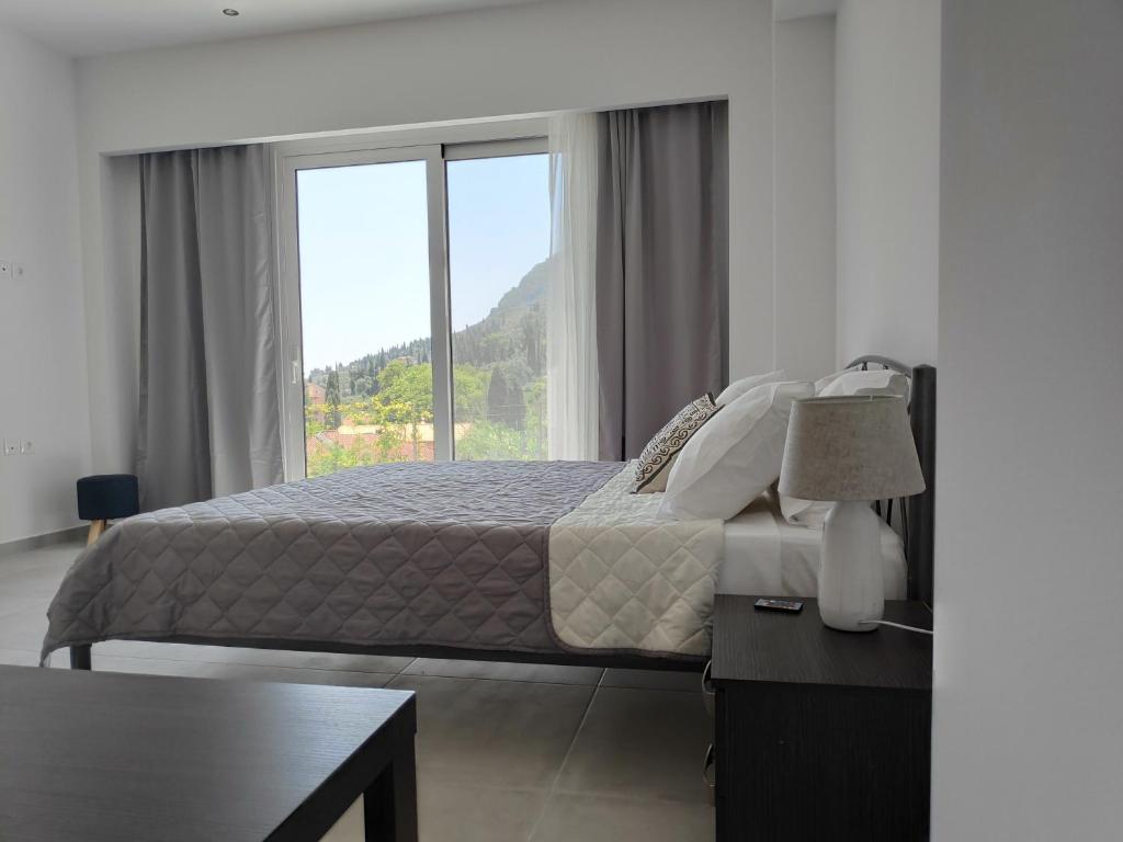 ein Schlafzimmer mit einem Bett und einem großen Fenster in der Unterkunft ALONI CORFU BENITSES in Benitses
