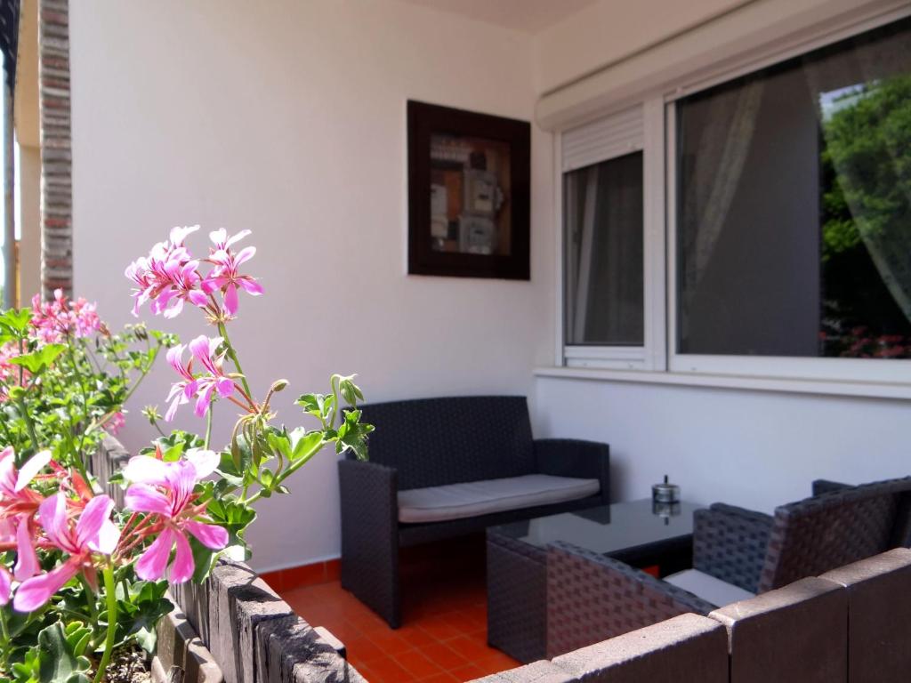 a porch with a chair and a window and flowers at Villa La Vita in Hévíz