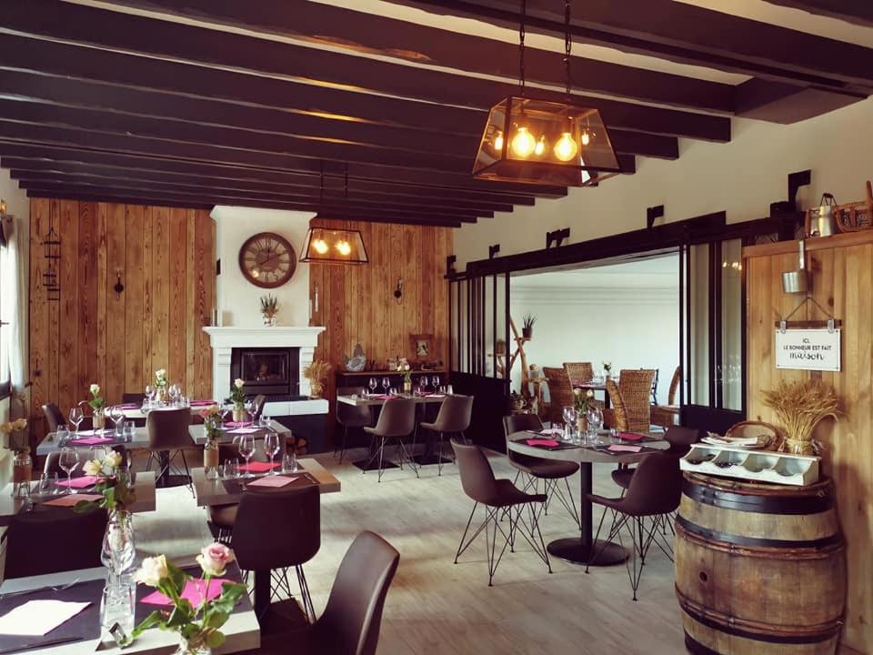une salle à manger avec des tables, des chaises et une cheminée dans l'établissement Auberge Saint-Jean, à Villequier-Aumont