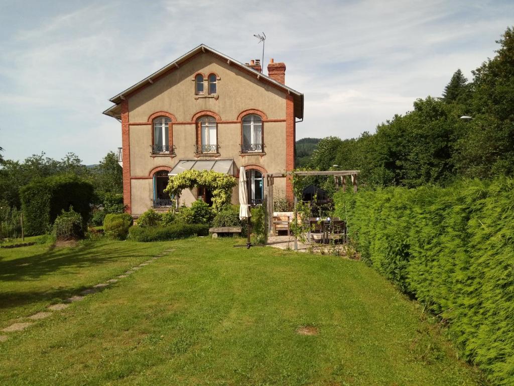 an old house with a yard in front of it at La Maison Du Marchand in Peyrat-le-Château